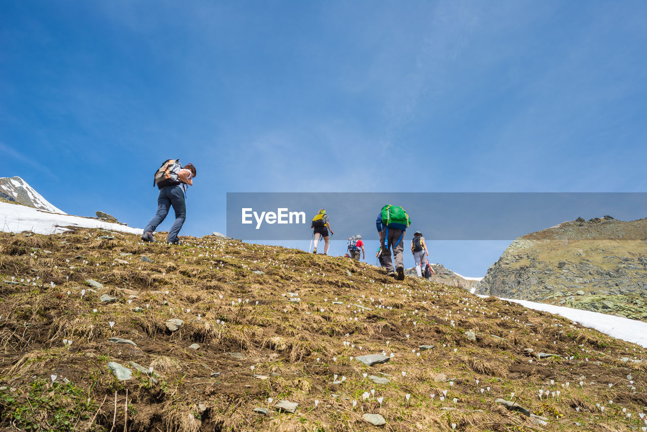 Low angle view of people on mountain against sky