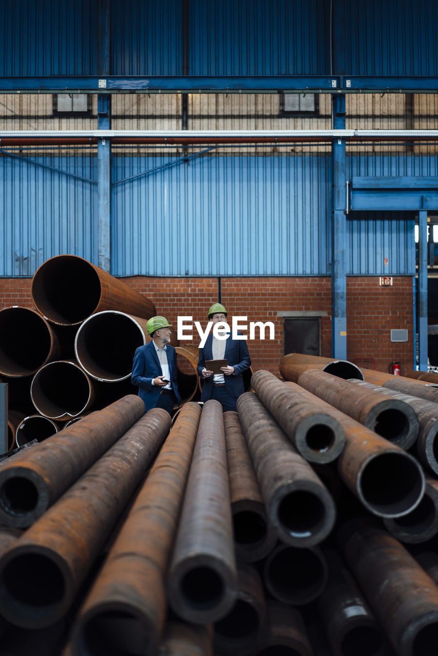 Male professionals working in pipe warehouse