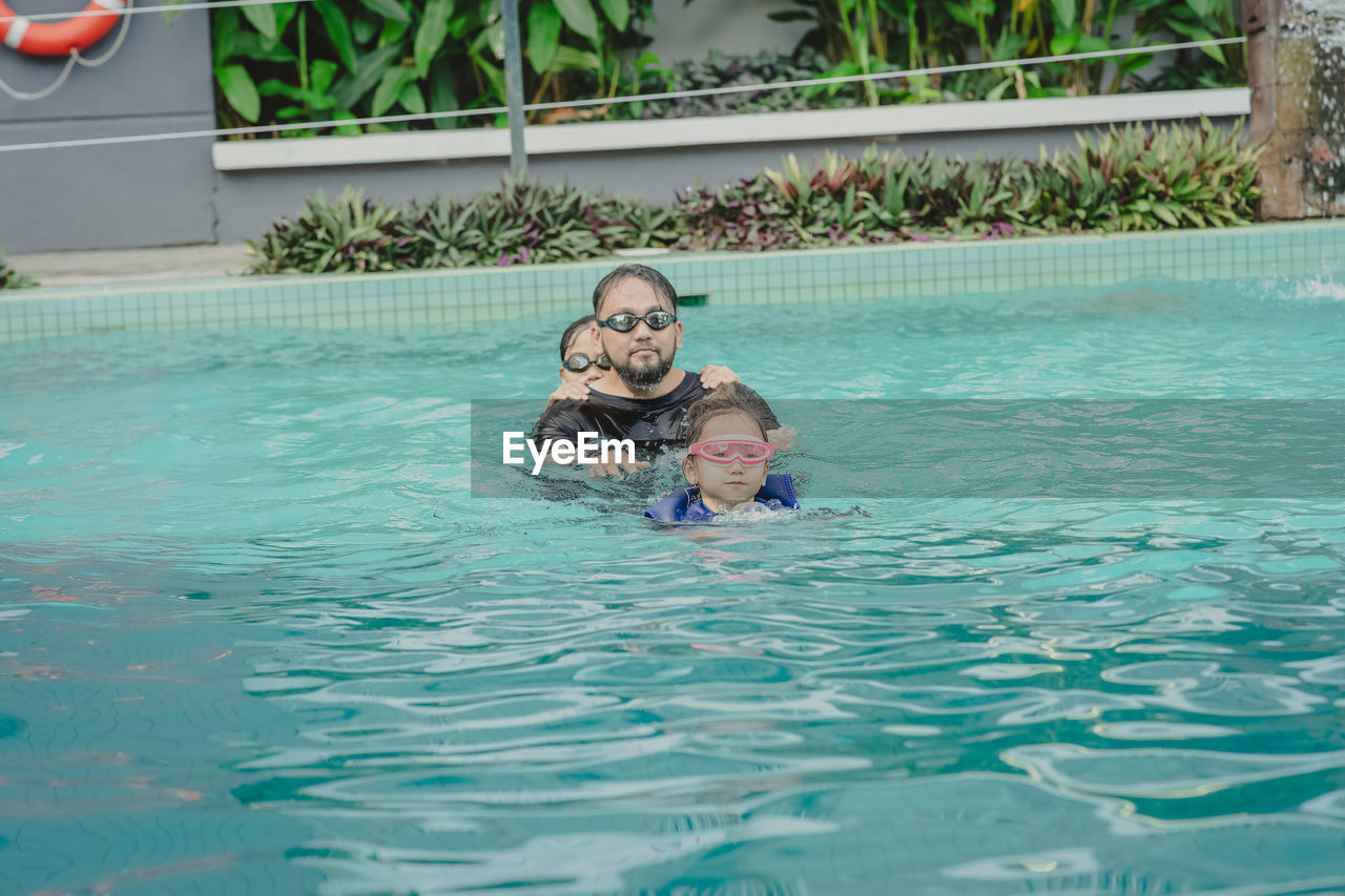 Family wearing goggles and swimming together in the pool.