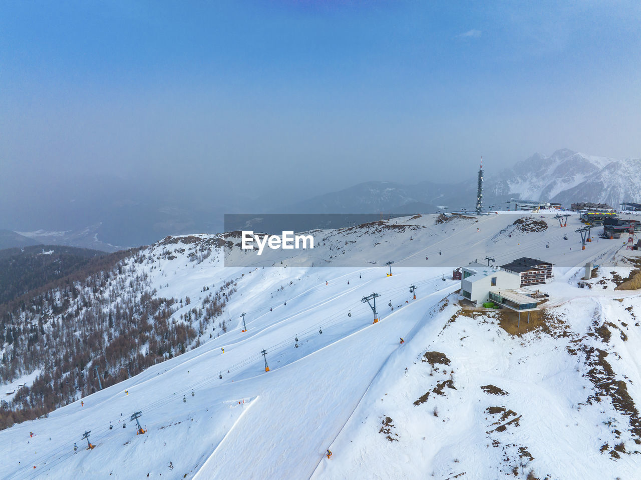 Aerial view of tourist attraction on snow covered mountain against blue sky