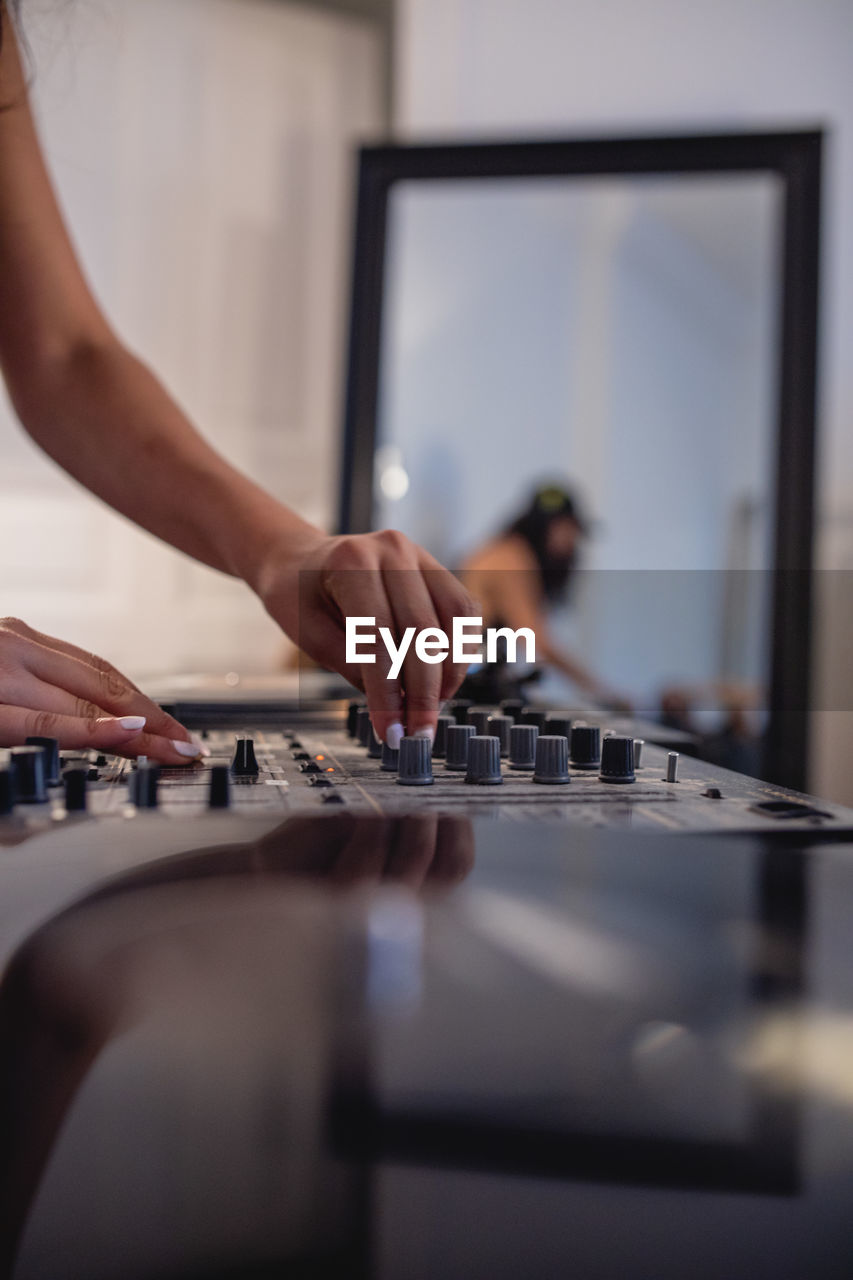 Cropped hand of woman playing sound mixer at home