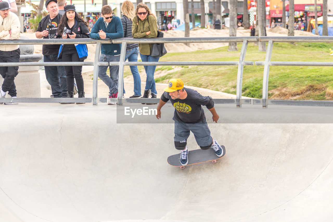 sports, recreation, full length, men, sports equipment, group of people, child, skateboard park, day, skateboard, skill, skateboarding, childhood, leisure activity, helmet, adult, youth culture, teenager, lifestyles, architecture, headwear, skateboarding equipment, women, balance, young adult, adolescence, enjoyment, casual clothing, sports helmet, fun, standing, person, footwear, outdoors, extreme sports, large group of people, looking, togetherness, motion, copy space