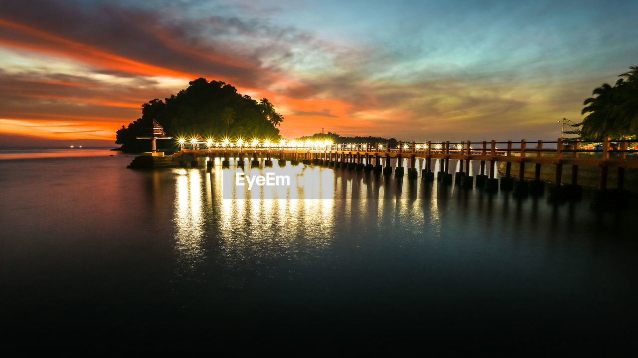 SILHOUETTE BUILT STRUCTURE BY SEA AGAINST SKY DURING SUNSET