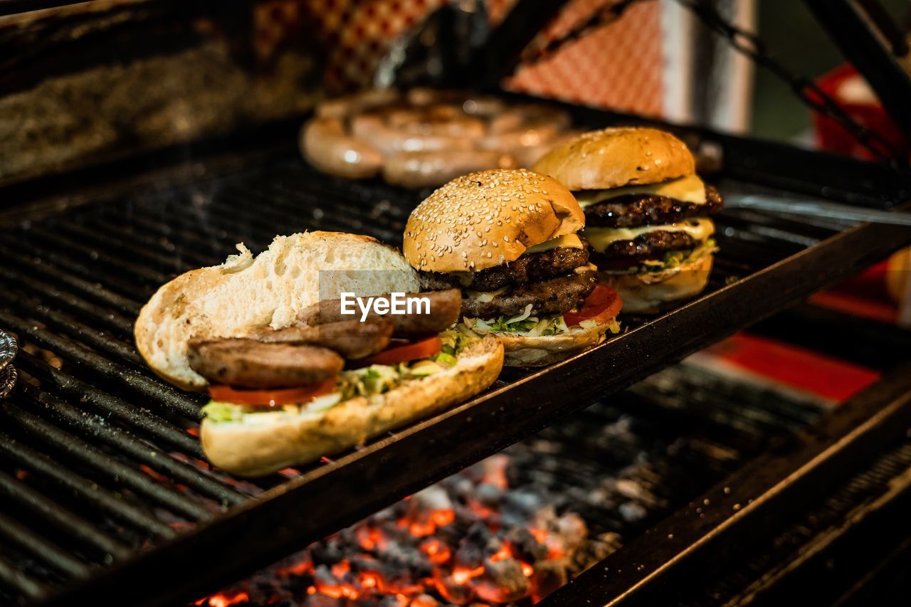 food, food and drink, barbecue, grilling, fast food, barbecue grill, grilled, meat, freshness, dish, cooking, sandwich, heat, hamburger, no people, unhealthy eating, meal, cuisine, burning, fire, beef, red meat, close-up, vegetable, focus on foreground, preparing food, flame, grid, grate, metal grate