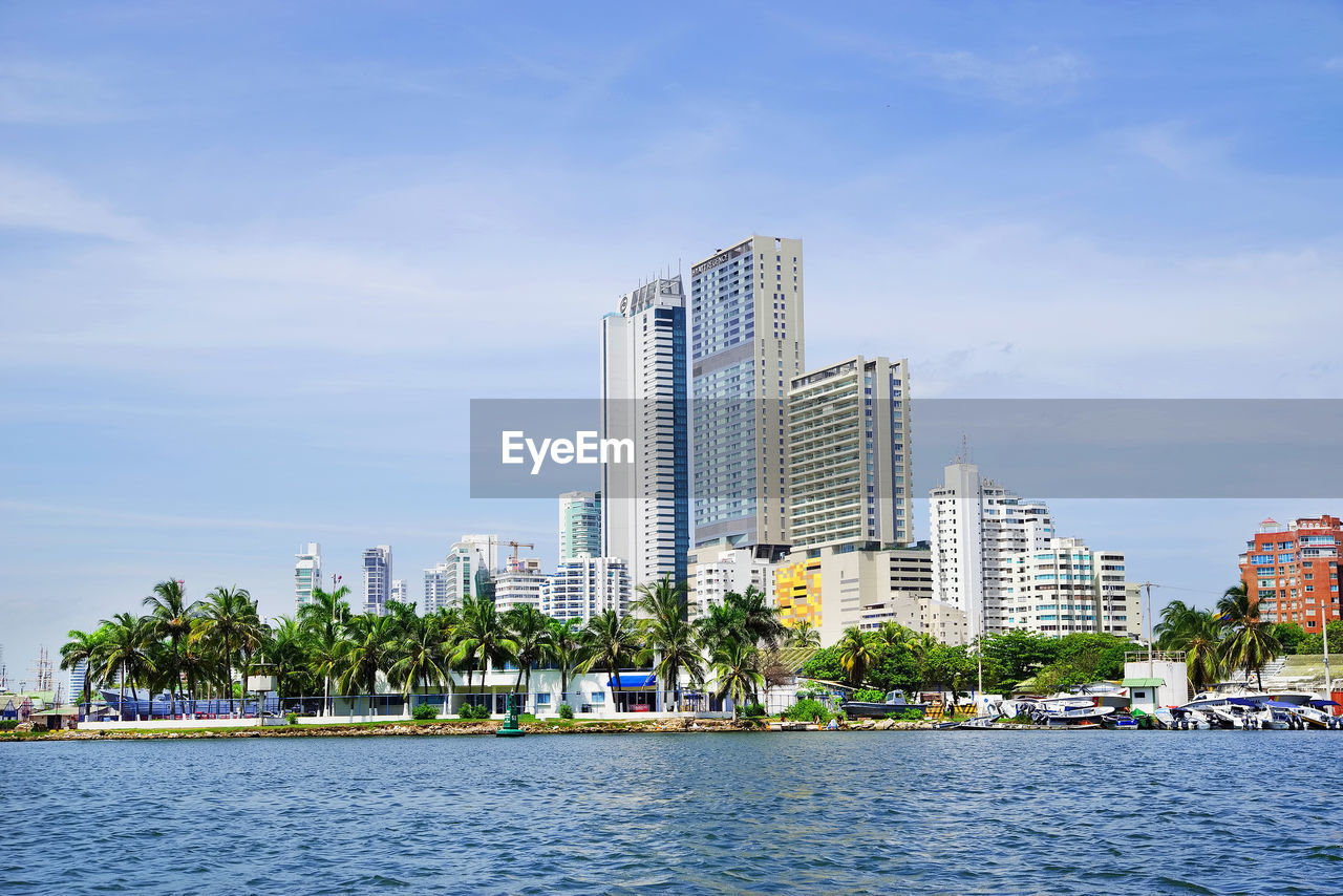 Modern buildings by river against sky