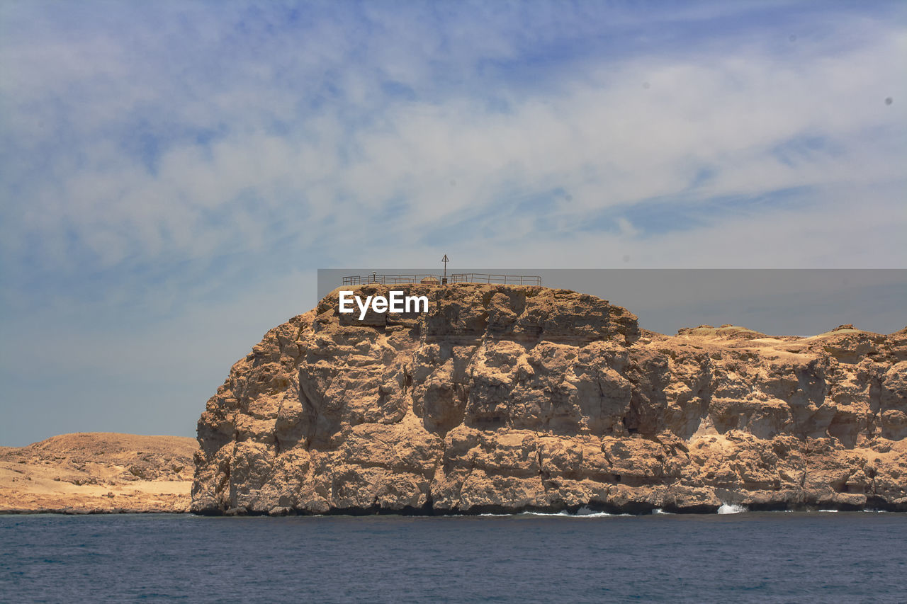 Rock formations by sea against sky