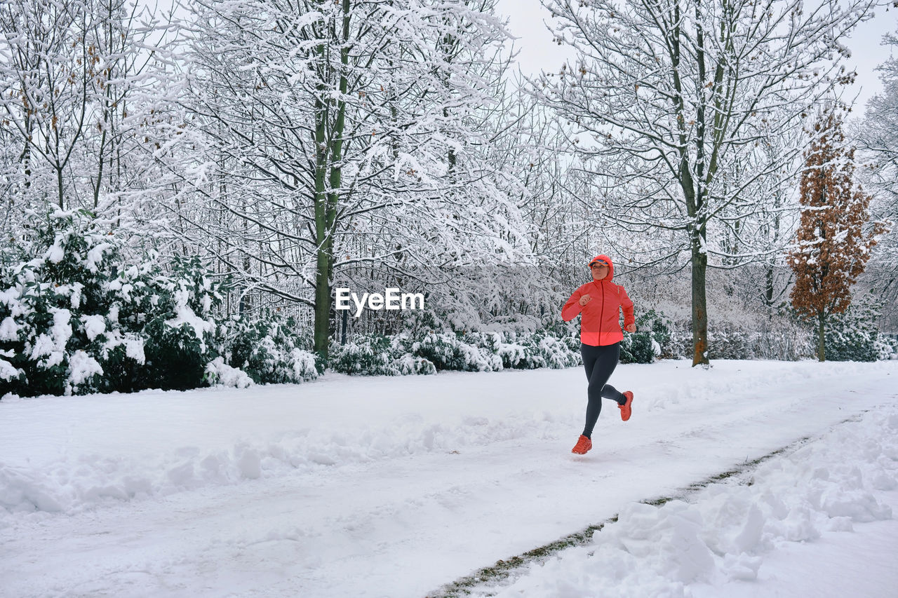 Running woman, girl runner on snow in park winter day. run, sport concept, leisure and freedom.