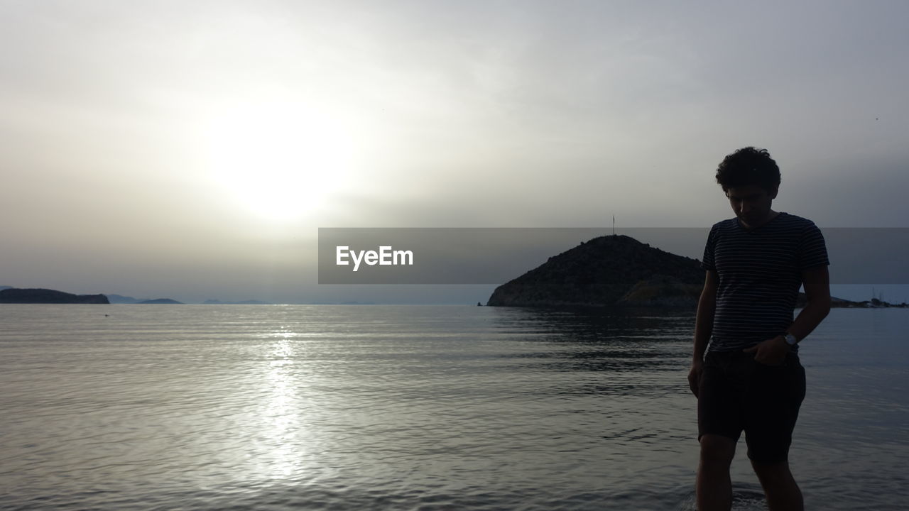 Man walking against sea during sunset