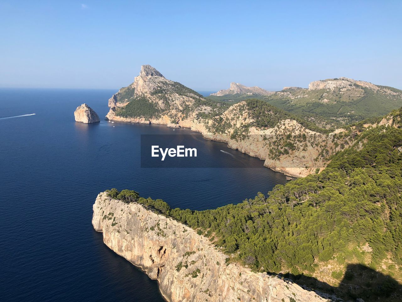 Scenic view of sea and mountains against clear blue sky