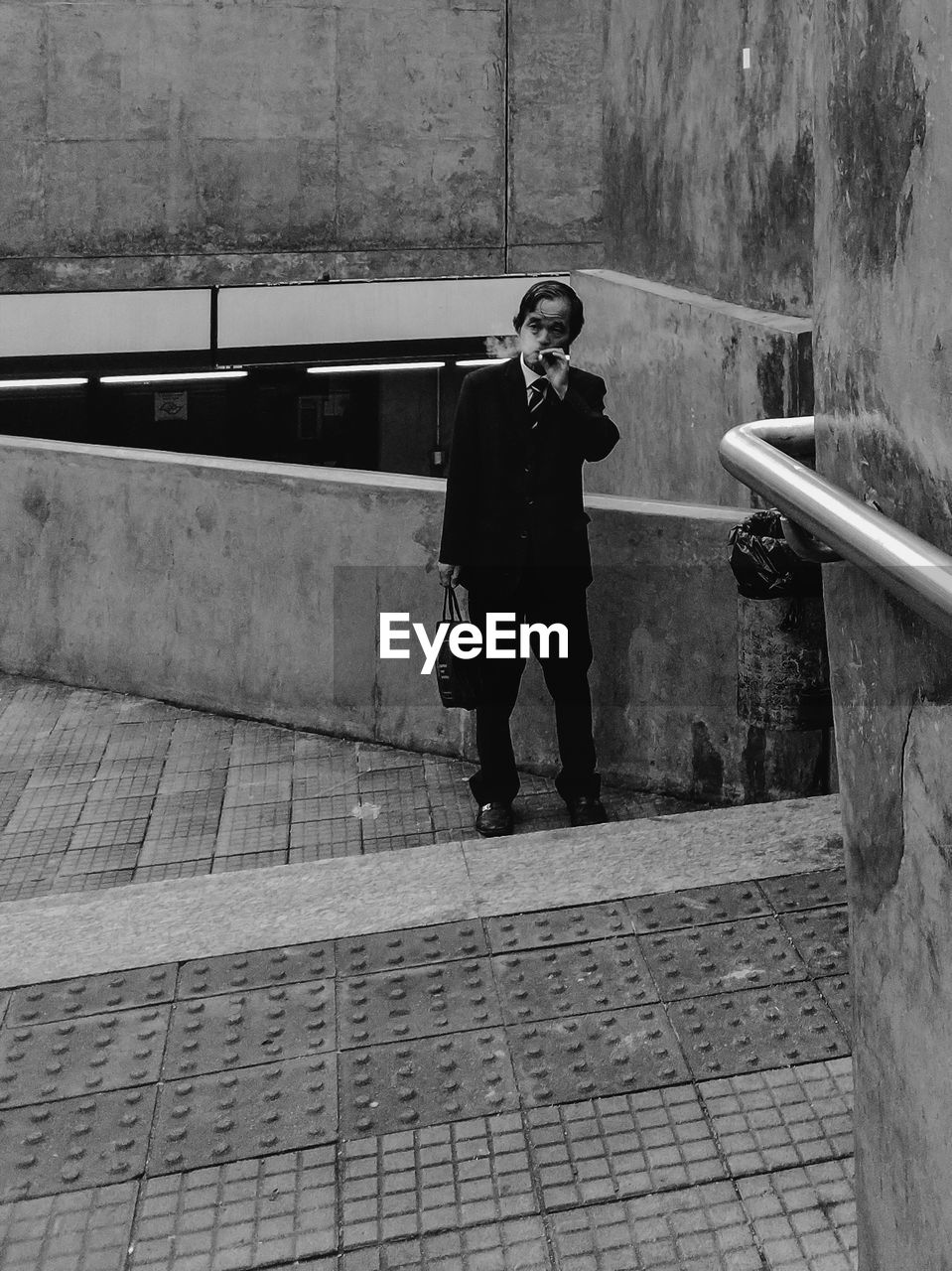 MAN STANDING ON FOOTPATH BY RAILING