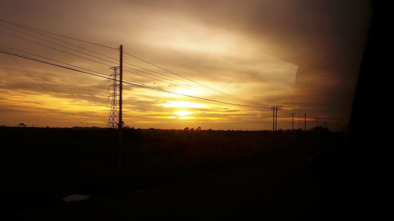 SILHOUETTE OF ELECTRICITY PYLONS ON LANDSCAPE