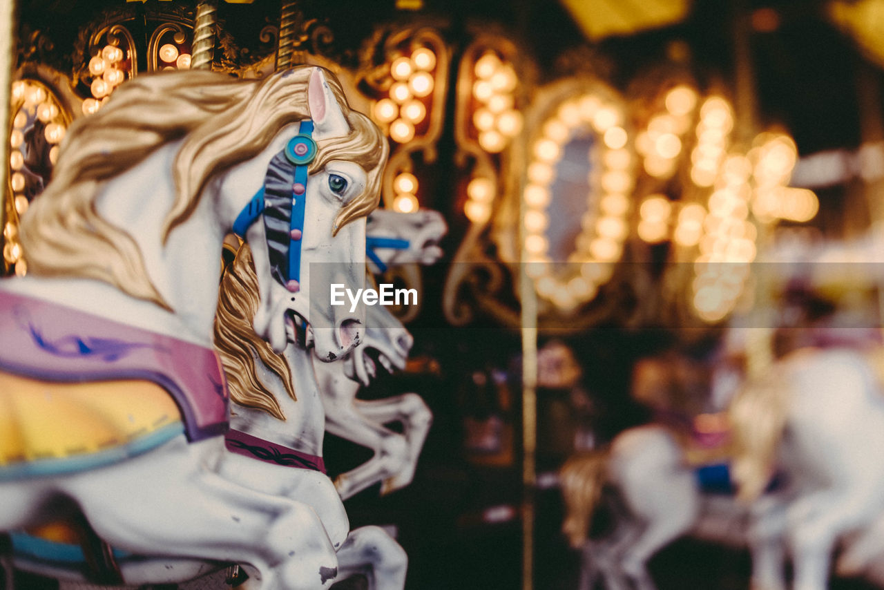 Close-up of carousel horse sculptures at illuminated amusement park