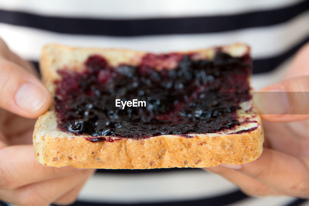Midsection of person holding jam spread on bread