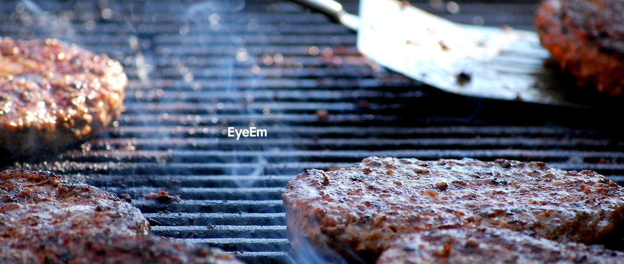 Hamburgers on an open grill outdoors.