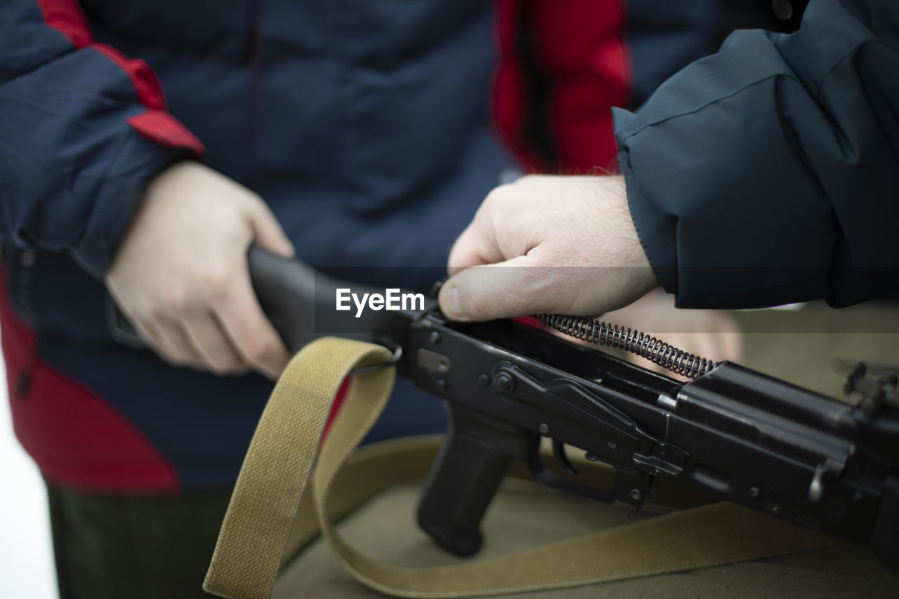 midsection of man holding gun while standing outdoors