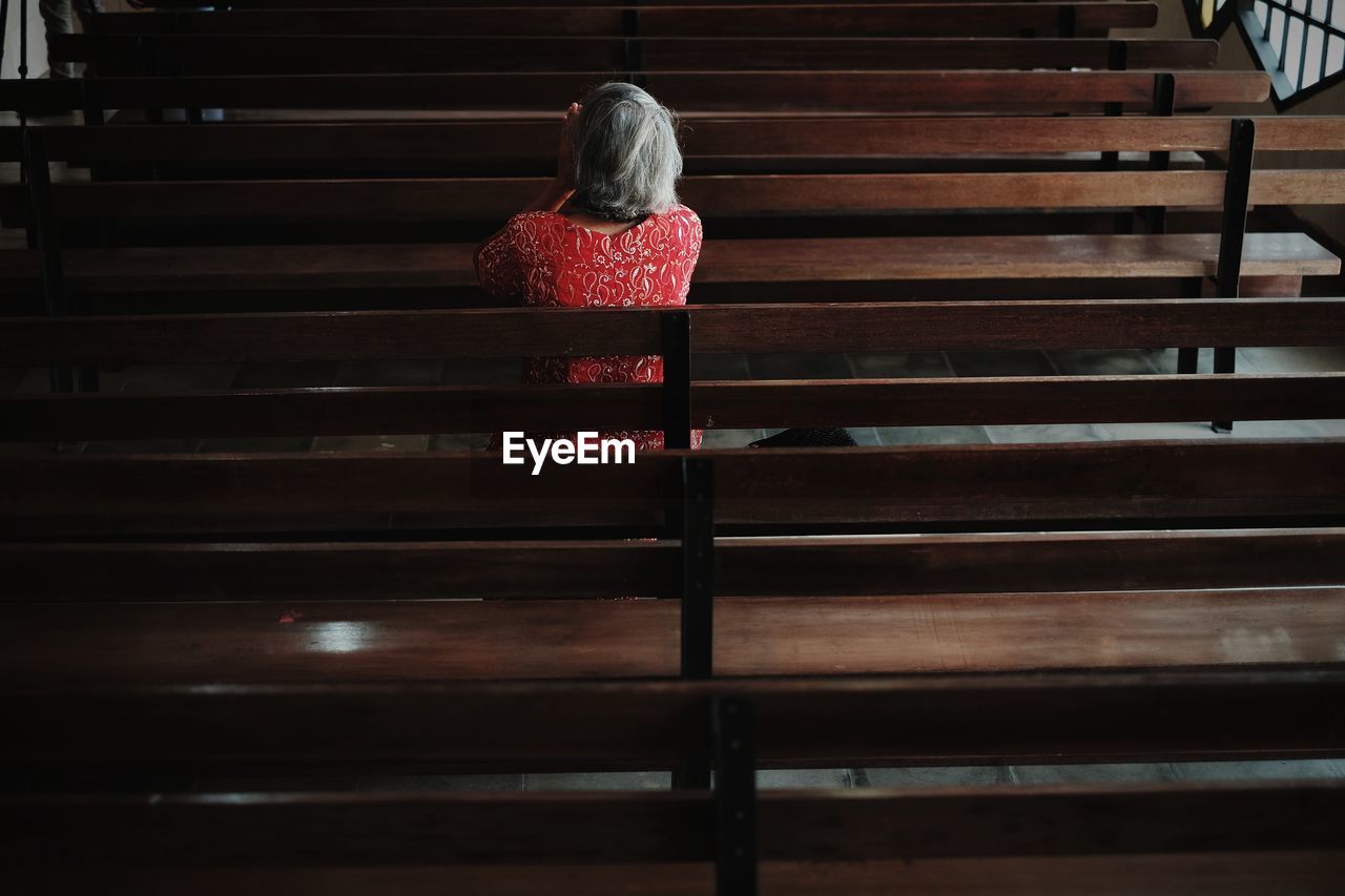 Rear view of woman sitting on pew at church