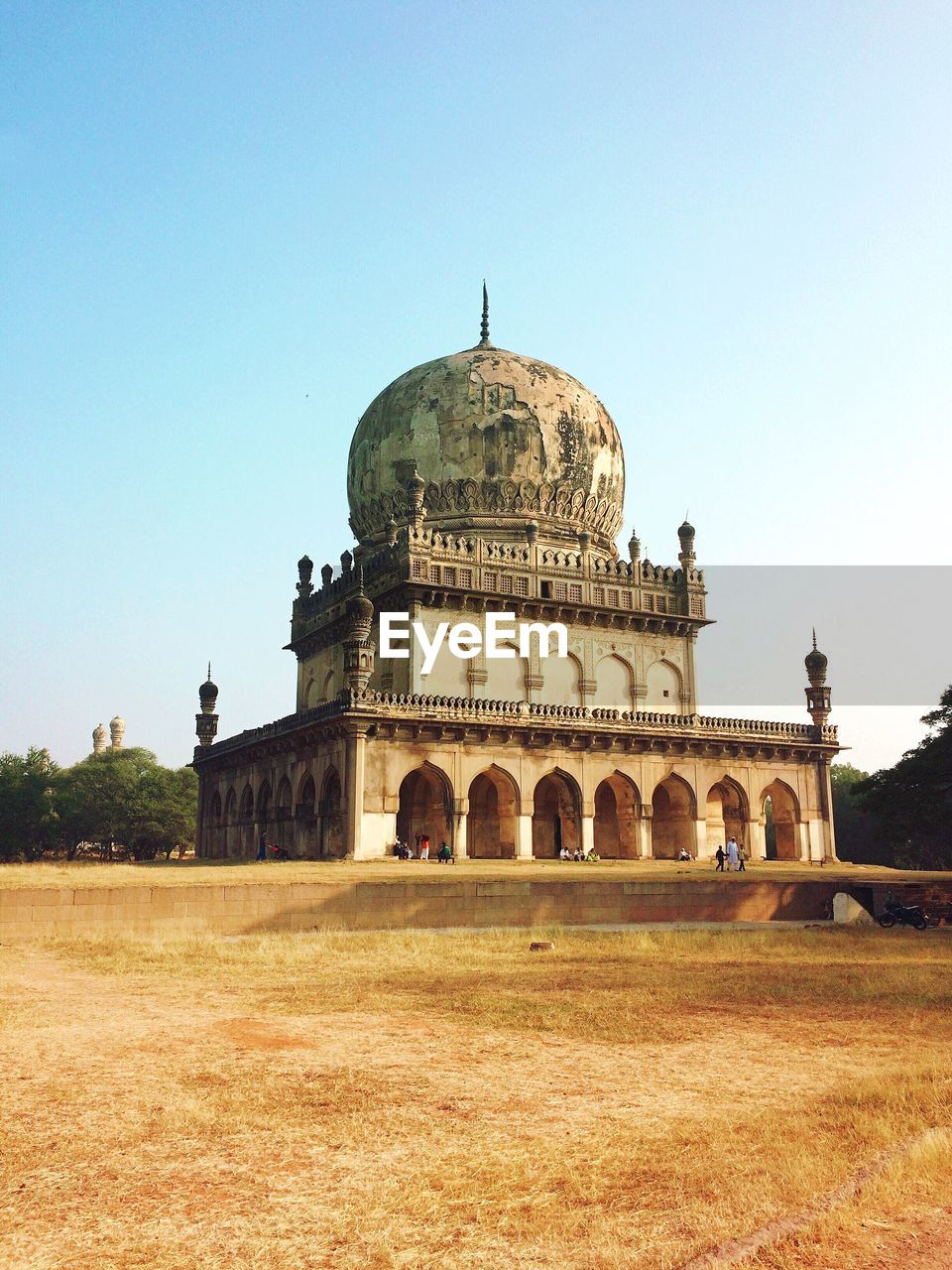 Low angle view of qutb shahi tomb by field against sky