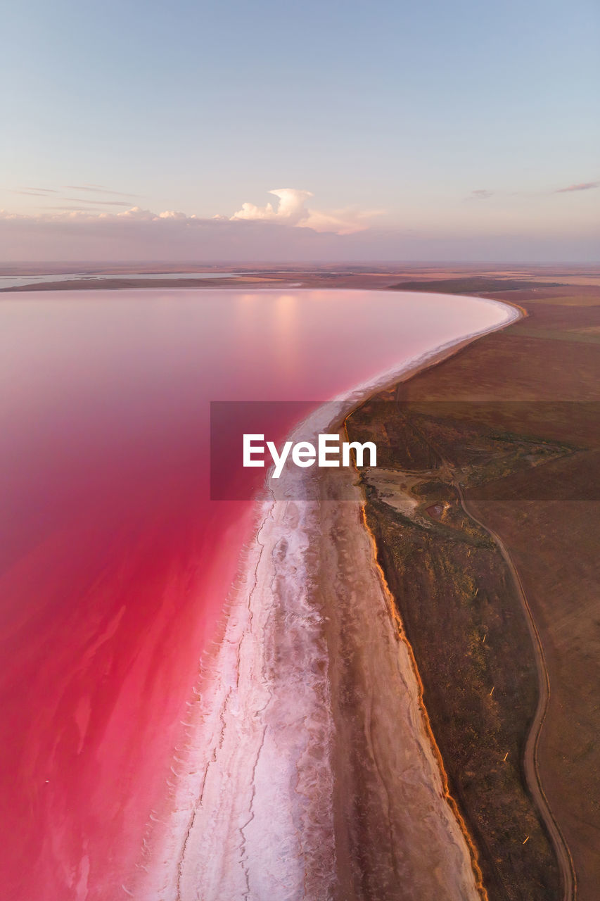 Vertical panoramic salty lake shore with pink salt at dusk after sunset. aerial view