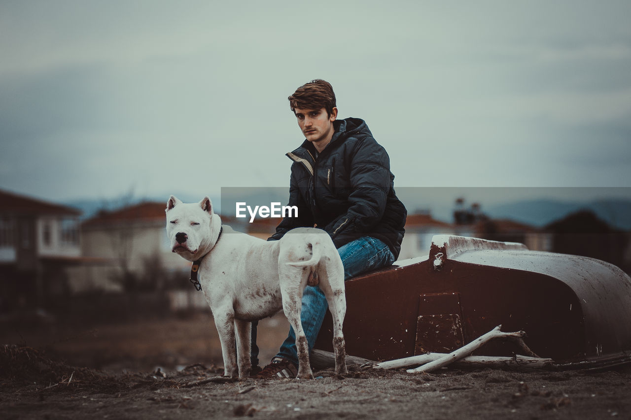 Man and dog on field against sky