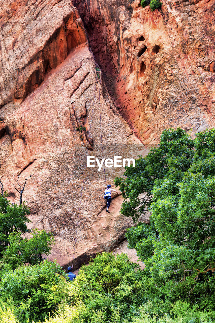 PEOPLE ON ROCK FORMATION BY MOUNTAIN