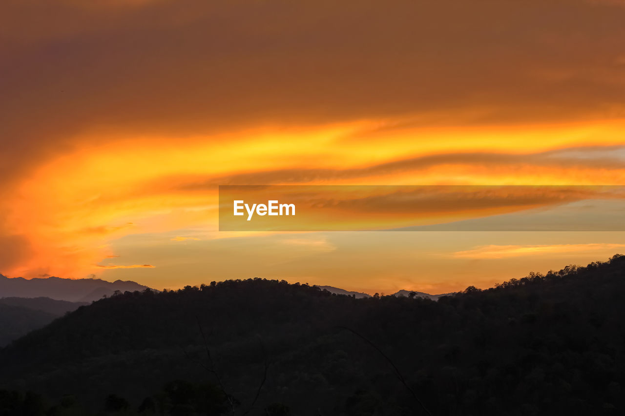 SILHOUETTE MOUNTAINS AGAINST ORANGE SKY