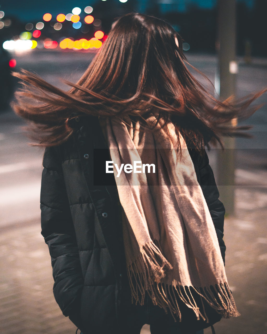 Woman tossing hair while standing in city at night