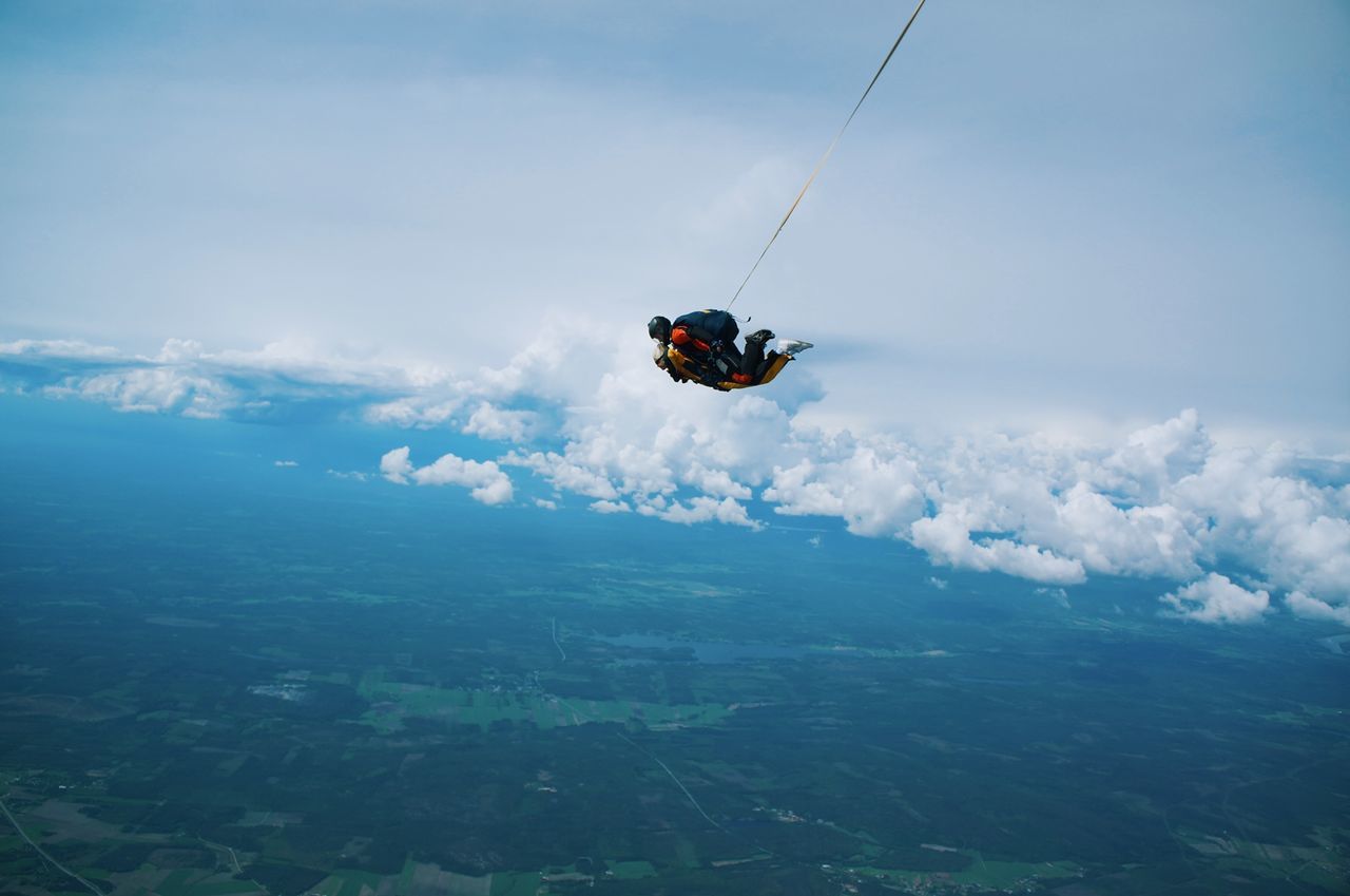 Friends paragliding in mid-air against sky