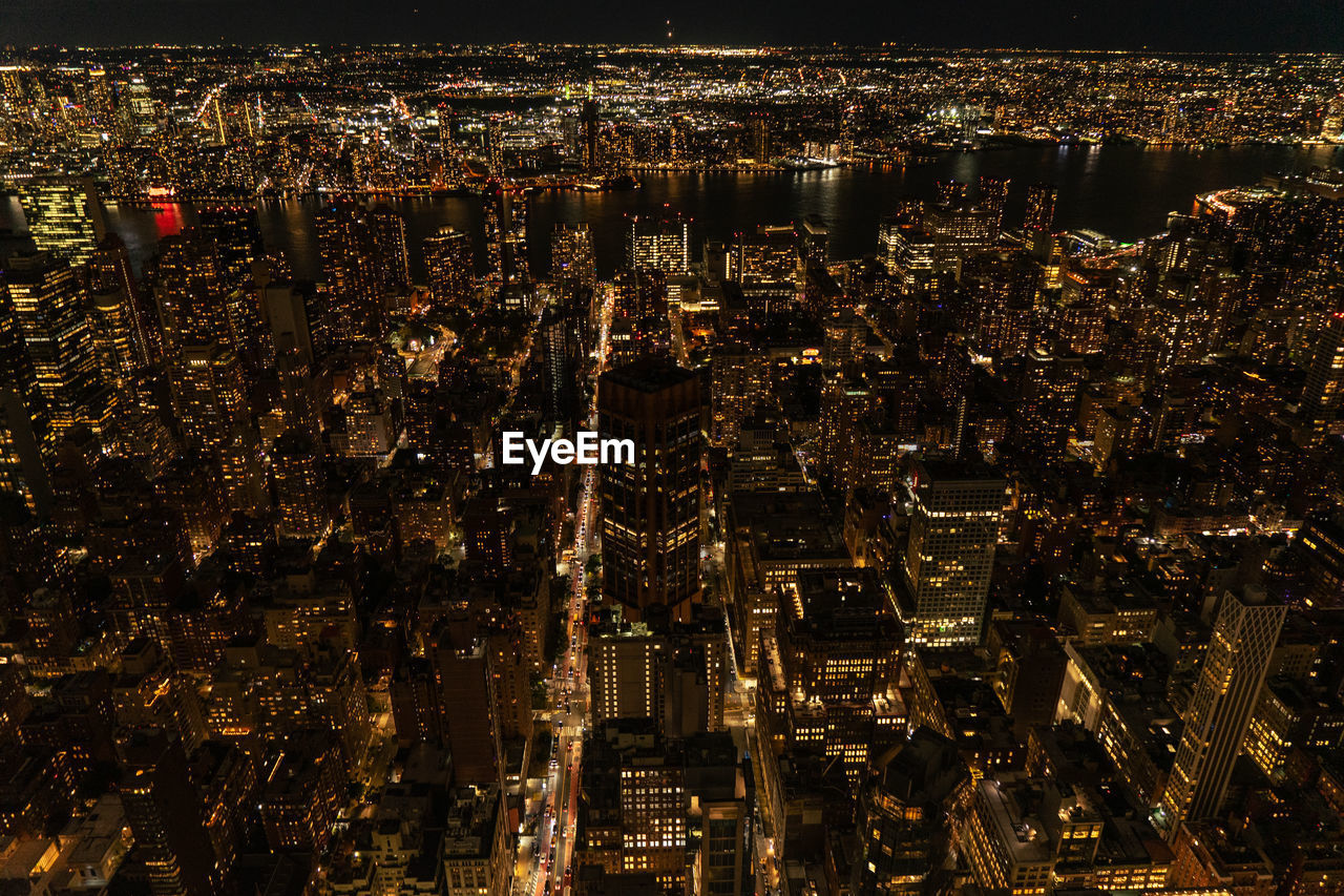 Aerial view of illuminated skyscraper buildings in city at night at high angle