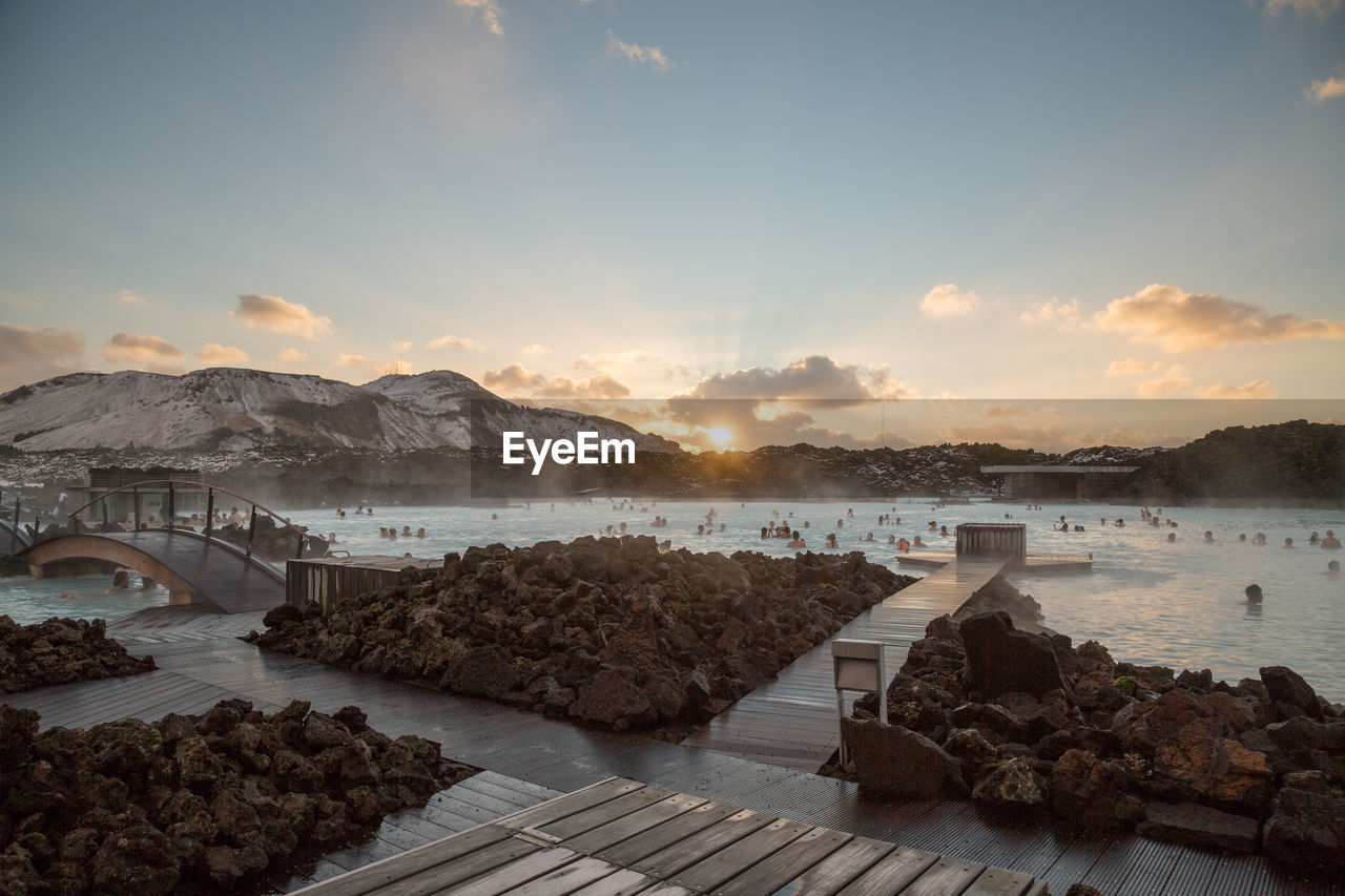 Scenic view of thermal spa by mountians during sunset