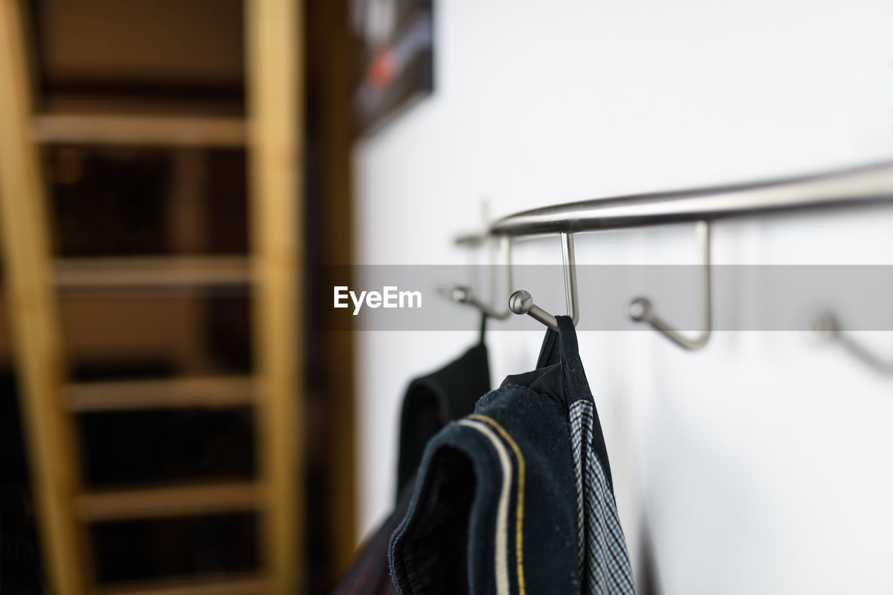 Close-up of clothes hanging on hooks on wall at home