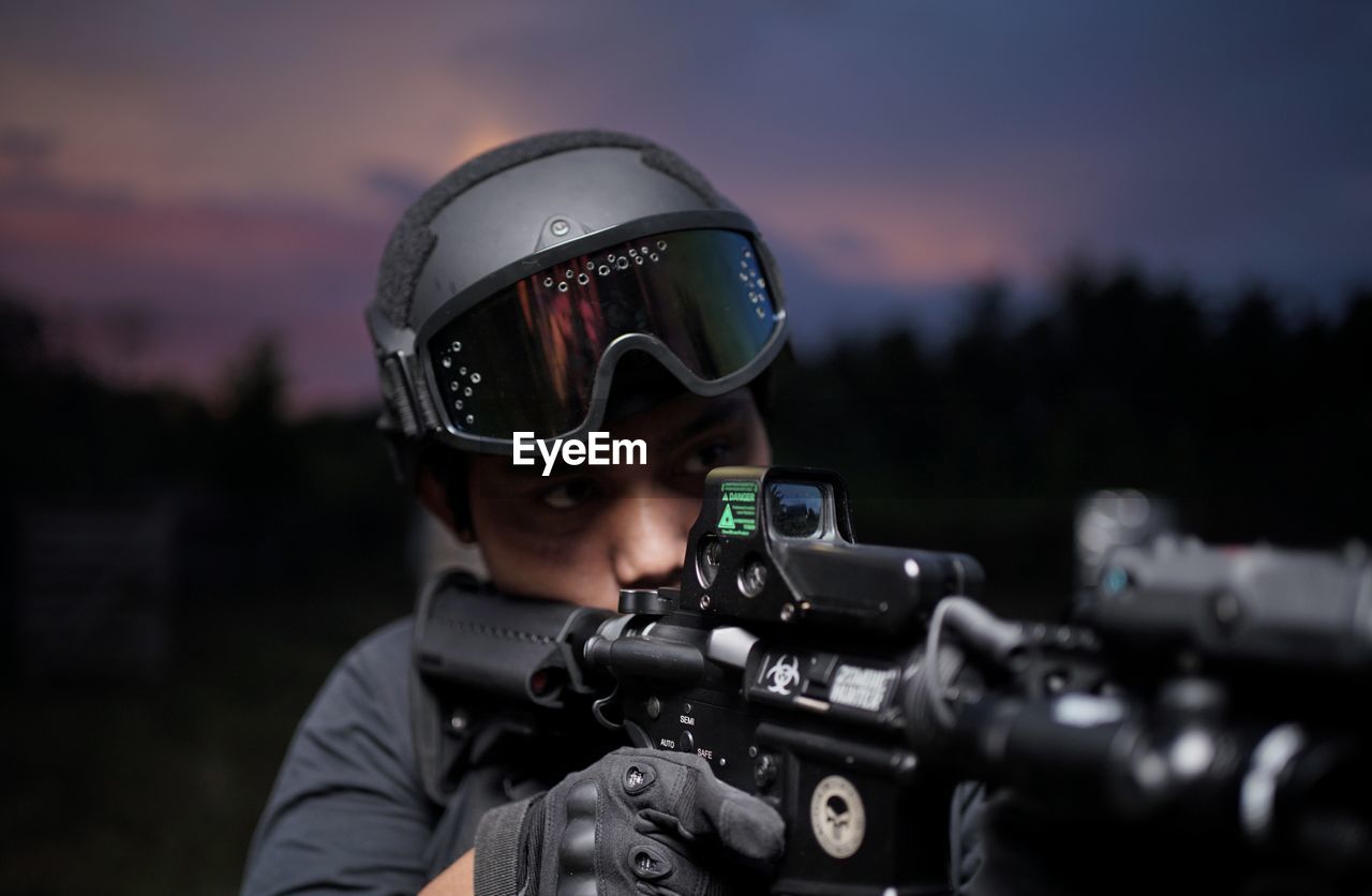 Rear view of man standing against sky with weapons and equipment at night