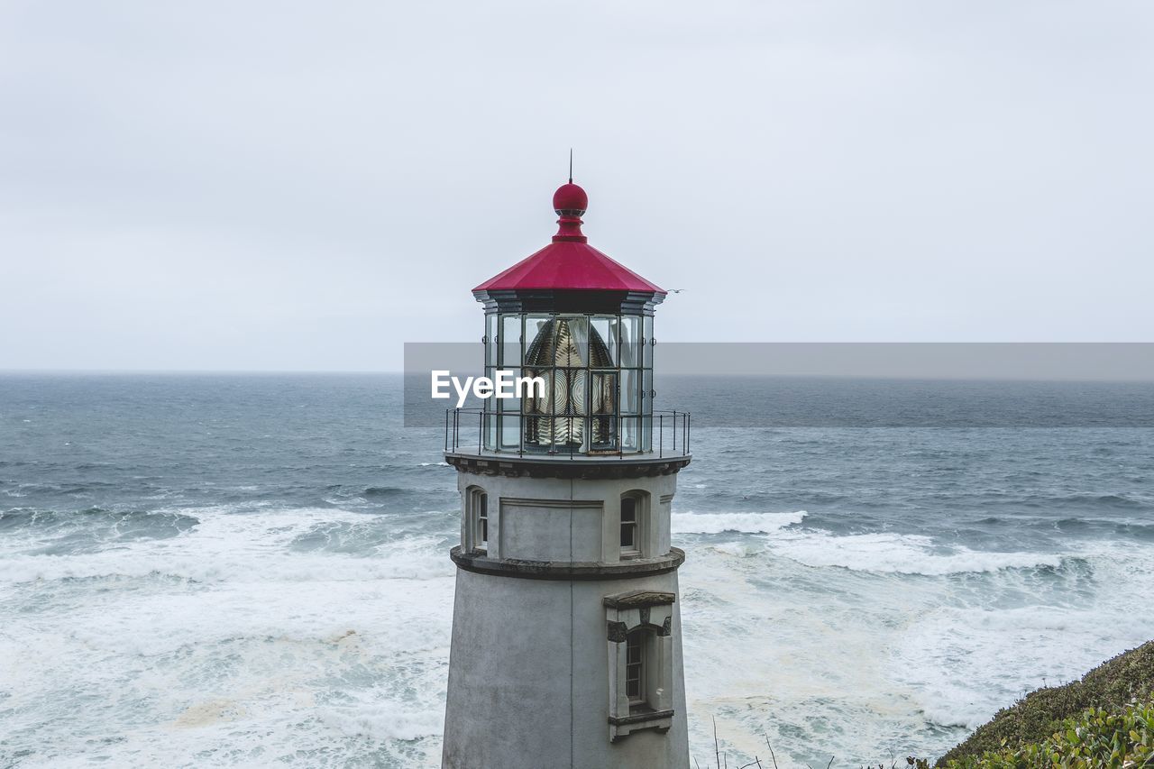 Lighthouse by sea against sky