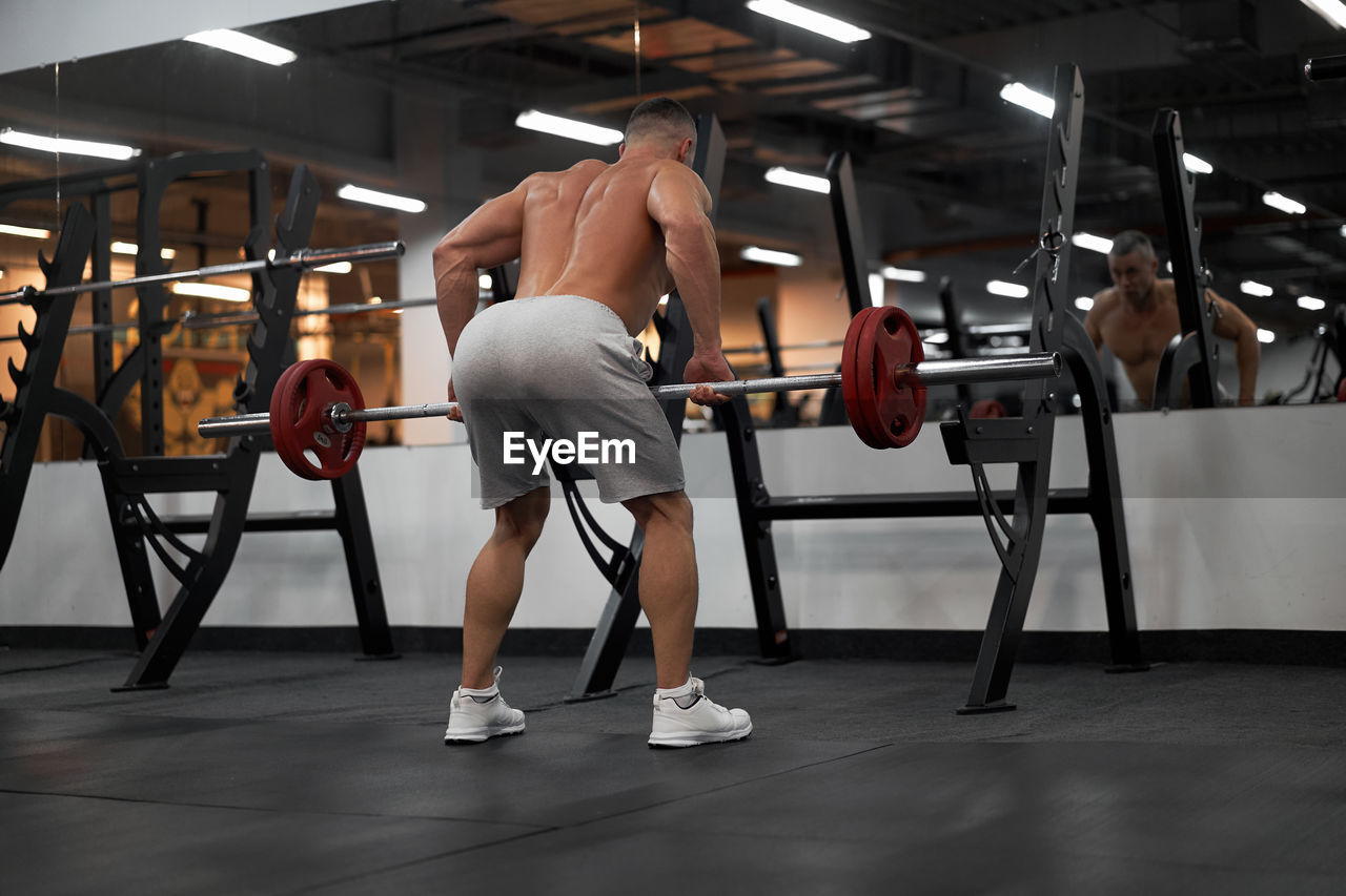 Rear view of shirtless man sitting in corridor