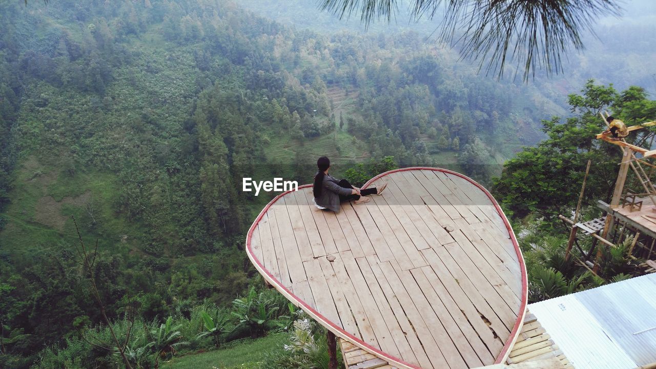 High angle view of woman sitting at observation point in forest