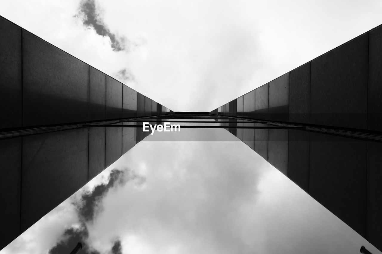 Directly below shot of glass building against cloudy sky