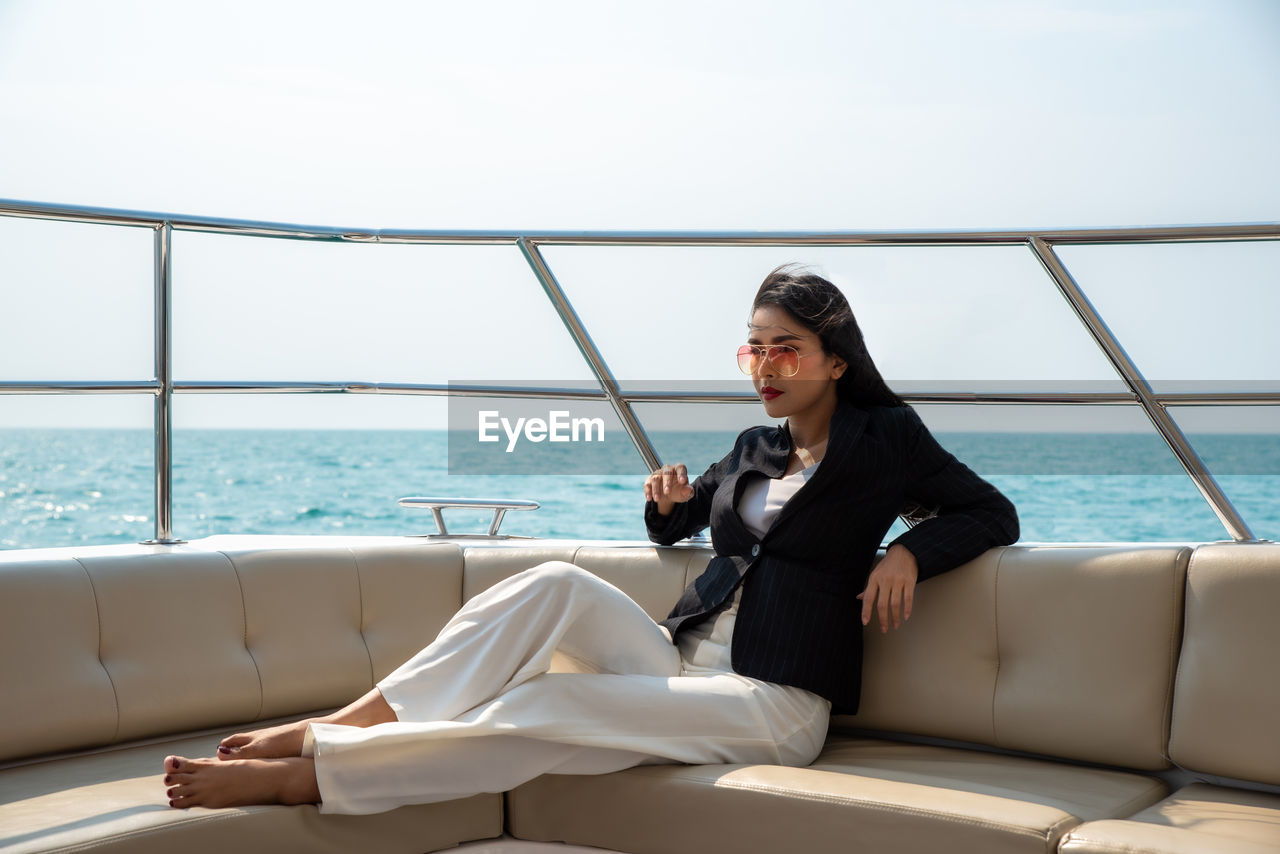 YOUNG WOMAN SITTING ON WINDOW AT SEA