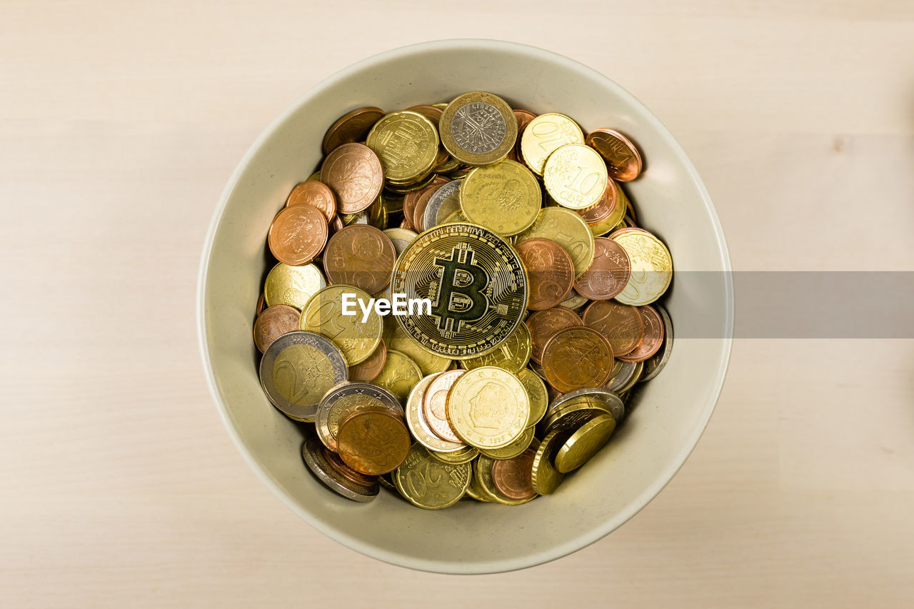 High angle view of coins with bitcoin in bowl