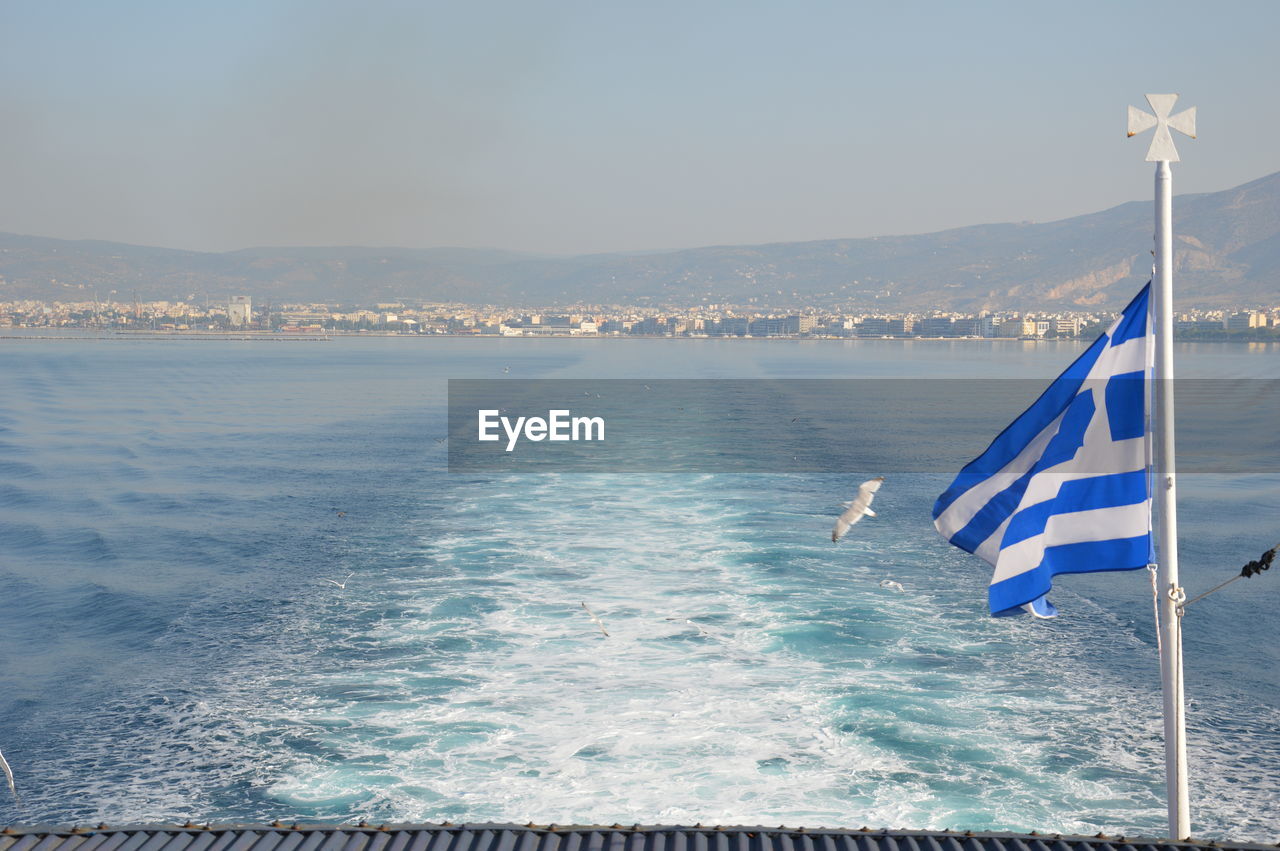 Greek flag on boat in sea against sky