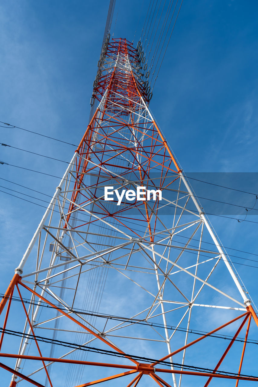 DIRECTLY BELOW SHOT OF ELECTRICITY PYLON AGAINST BLUE SKY