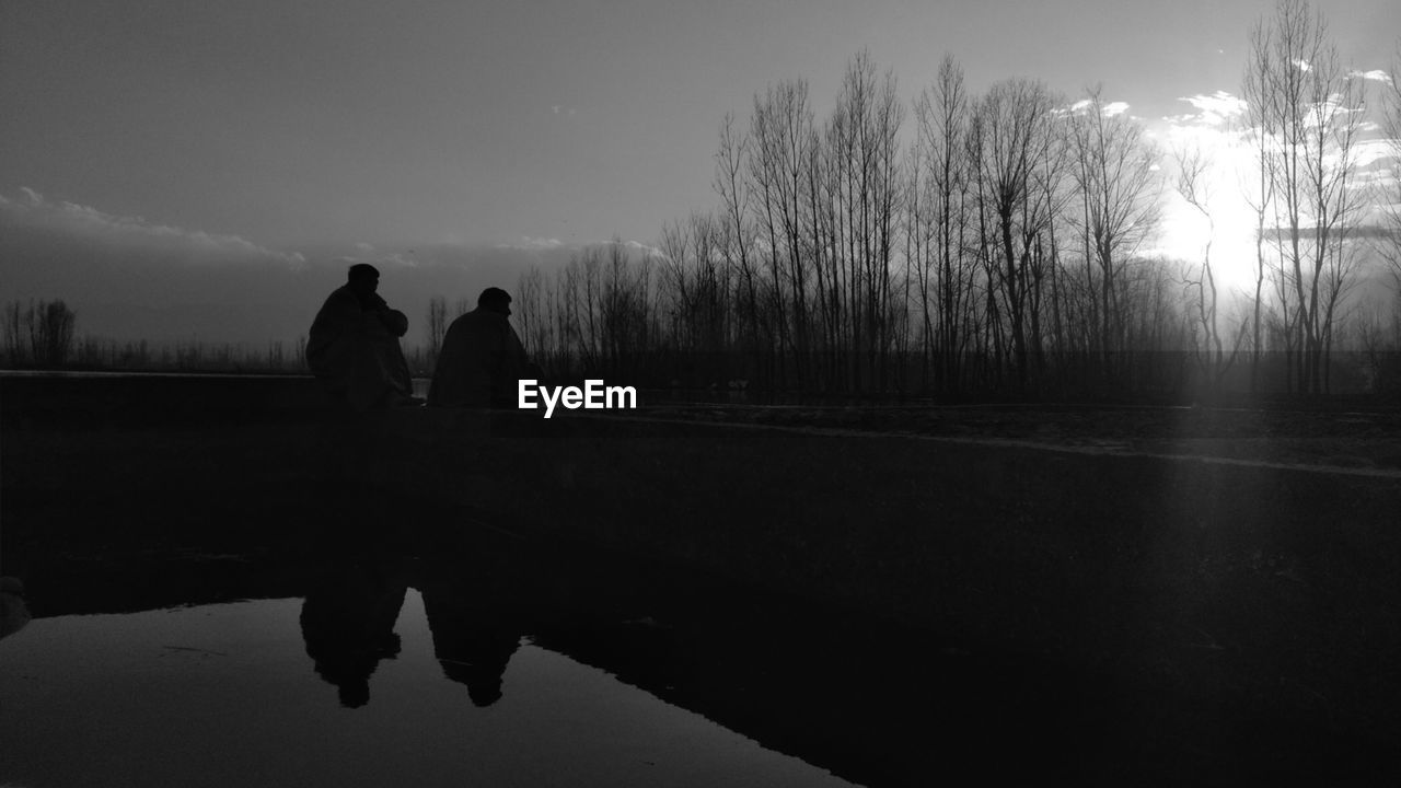 SILHOUETTE PEOPLE WALKING ON LAKE AGAINST SKY