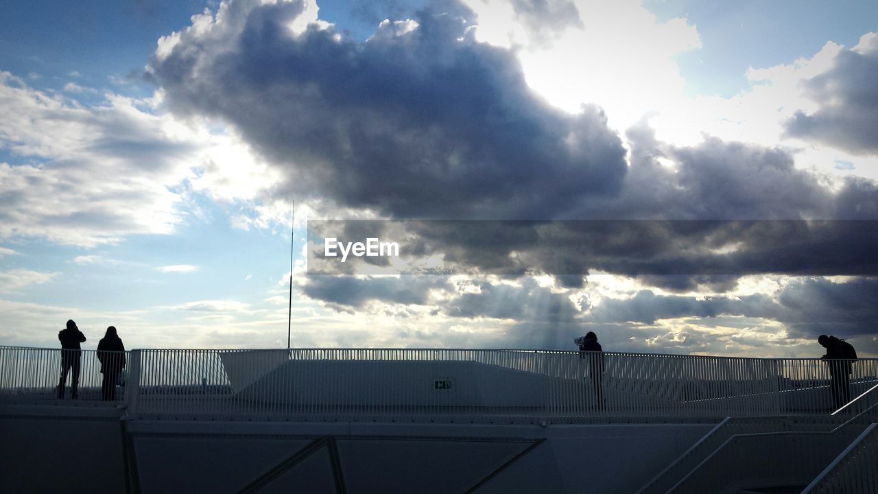 SILHOUETTE PEOPLE STANDING AGAINST SKY IN CITY