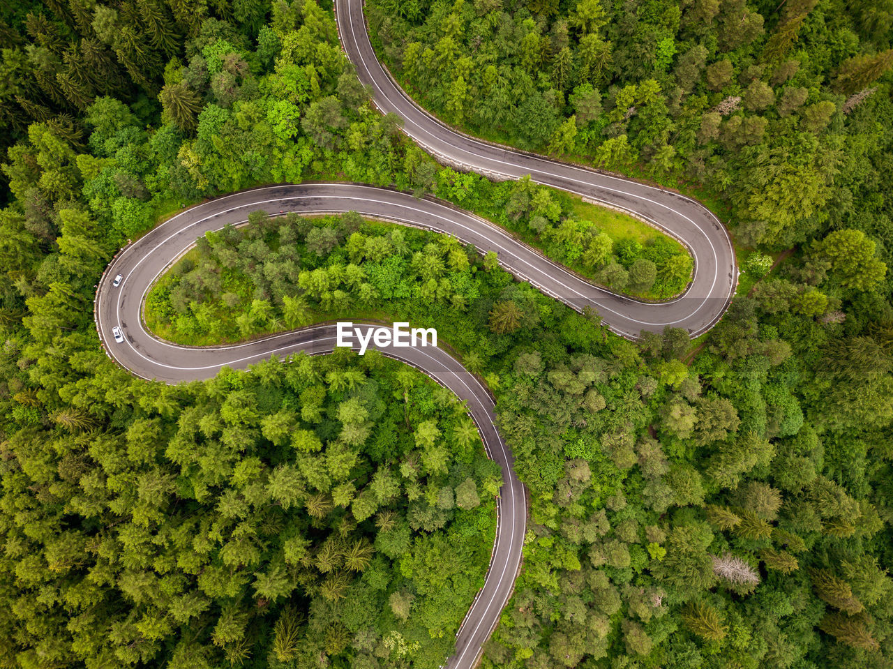 Winding road through the forest, from high mountain pass, in summer time. aerial view by drone.