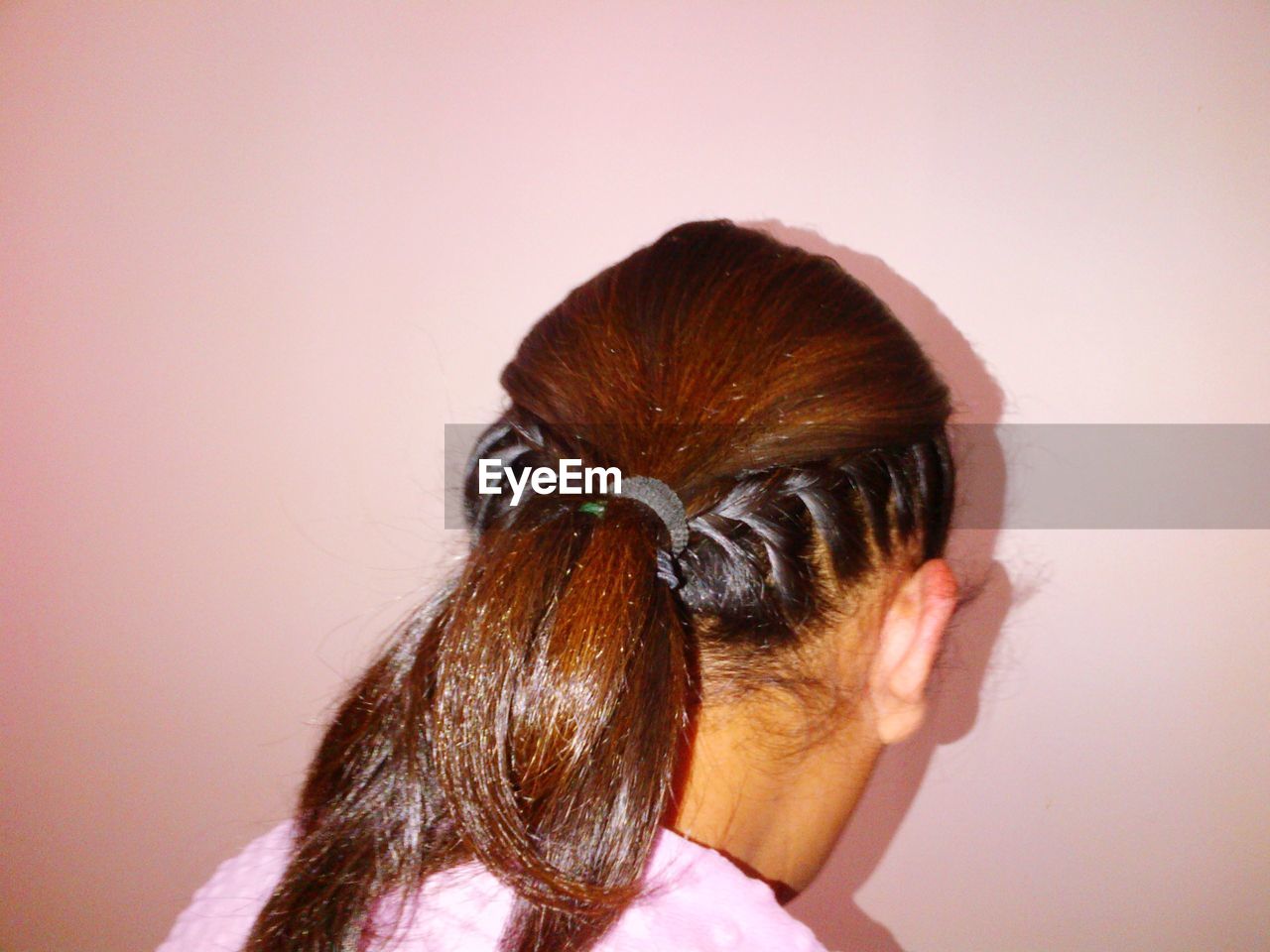 Close-up of woman with braided hairstyle against pink wall