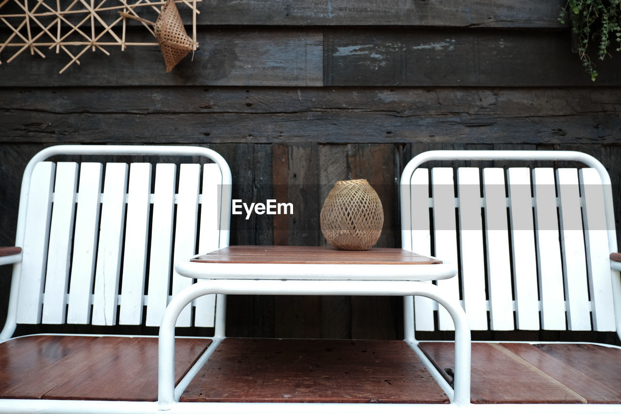 Empty chairs and table against wall