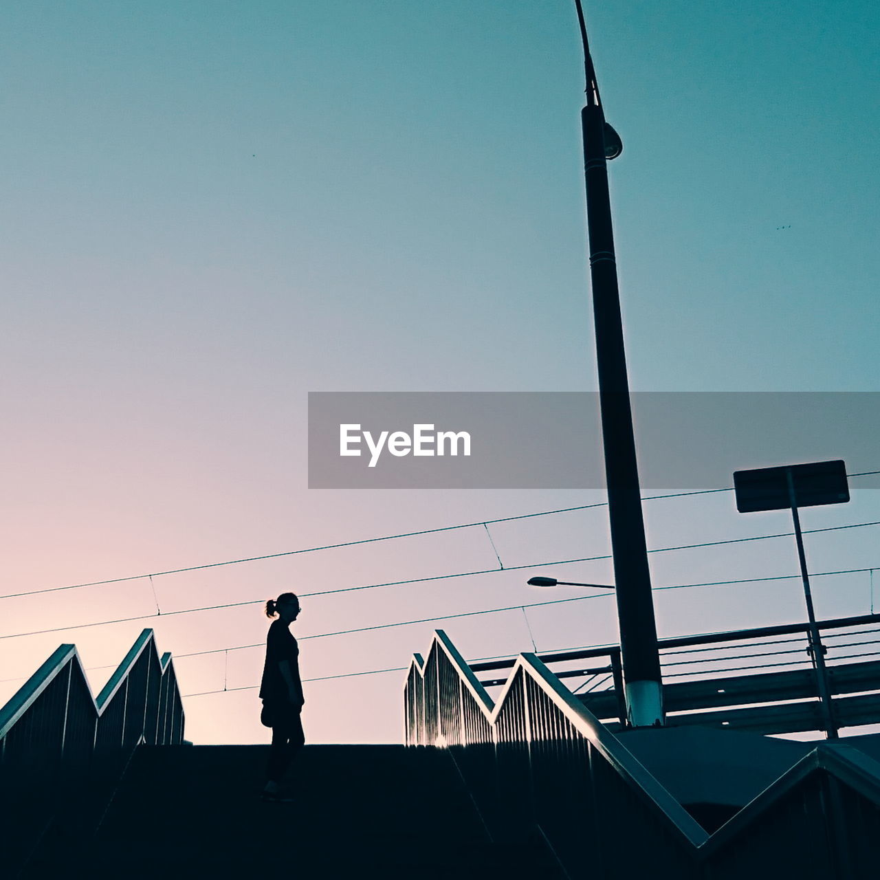 LOW ANGLE VIEW OF SILHOUETTE WOMAN STANDING AGAINST SKY DURING SUNSET