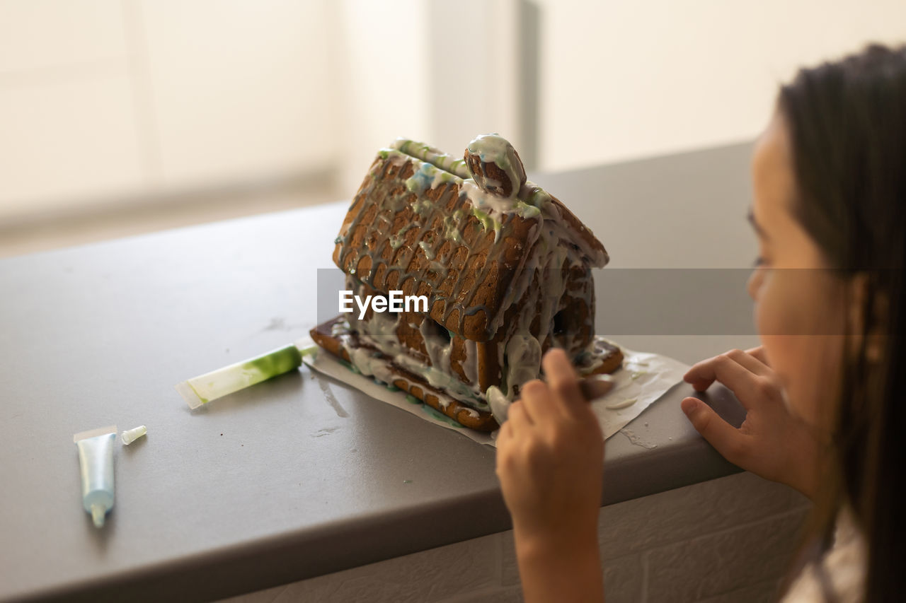 A girl plays with a gingerbread house for traditional christmas decoration