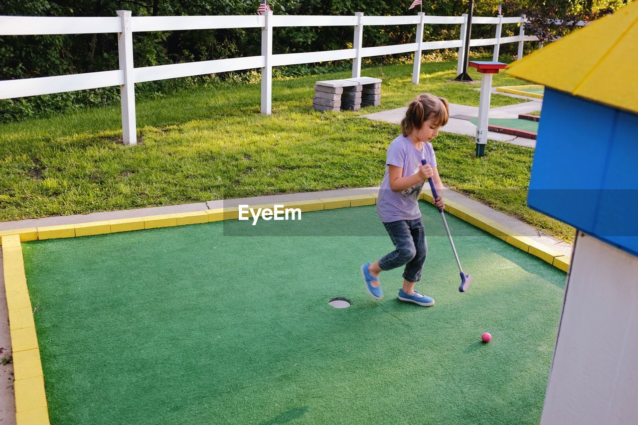 Full length of girl playing miniature golf at lawn