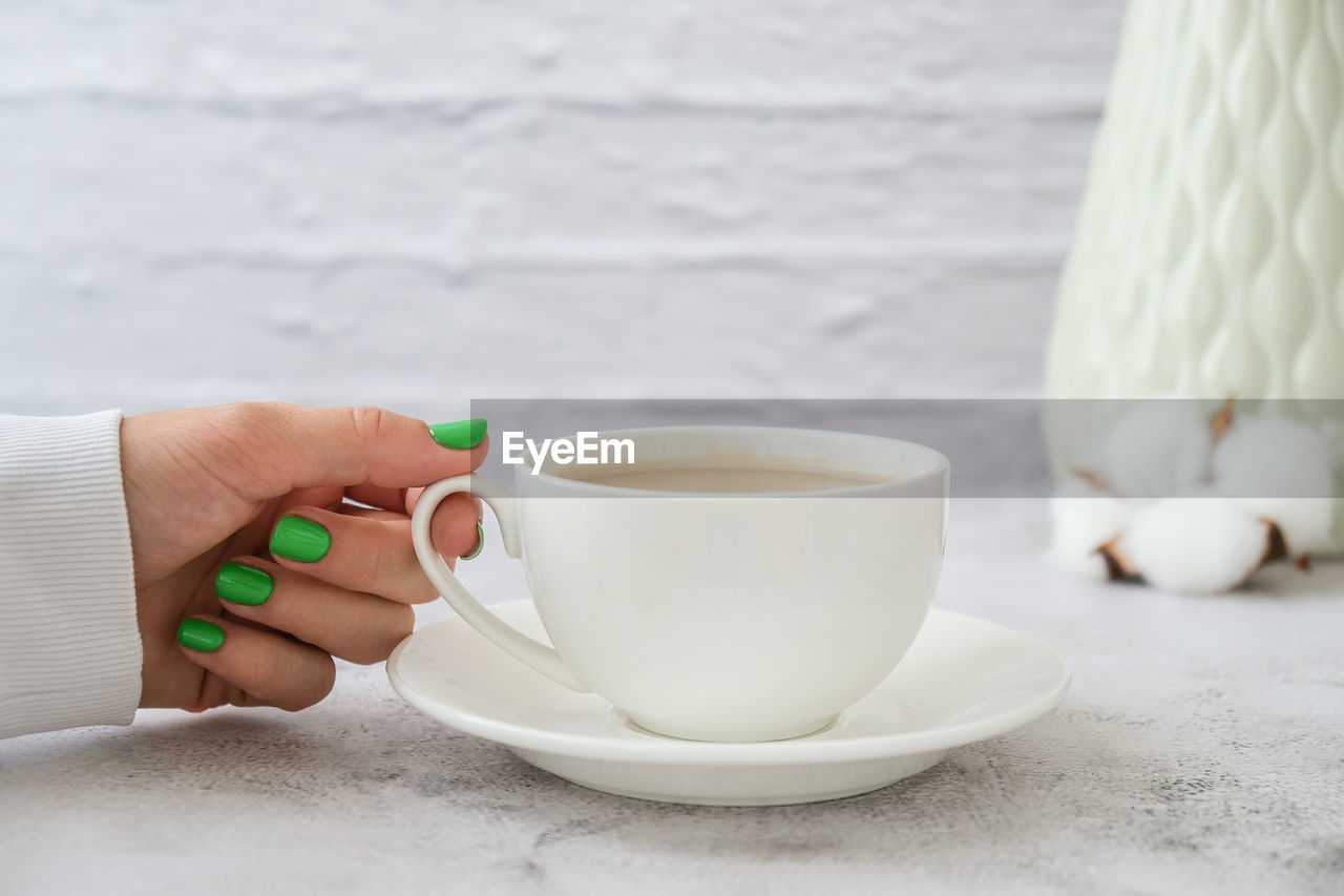 Midsection of woman holding coffee cup on table