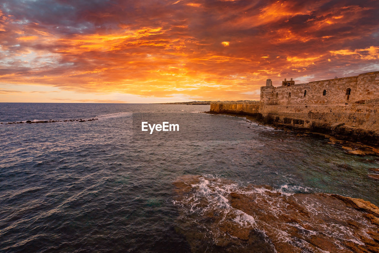 Sunset over the sea with maniace castle in ortigia