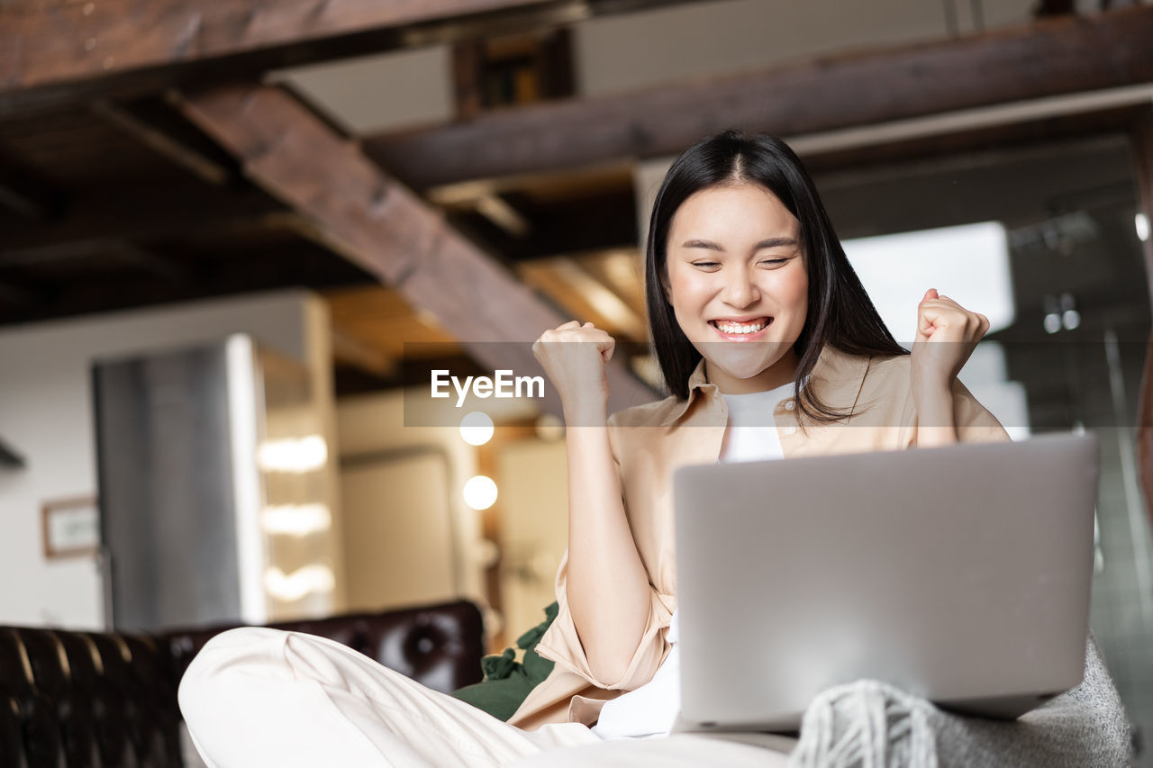 young woman using laptop while sitting on sofa